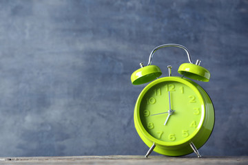 Green alarm clock on a grey wooden table