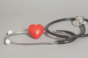 Red heart with a medical stethoscope on gray background