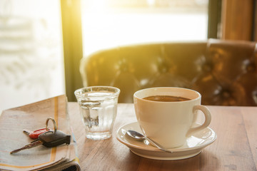White coffee cup , Newspaper, car key  and glass water on wooden