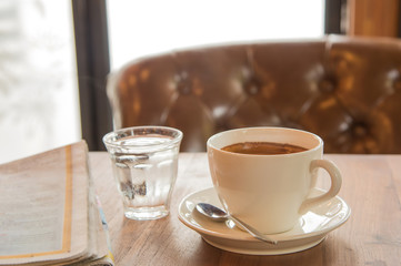 White coffee cup ,Newspaper and glass water on wooden table.