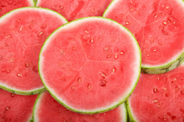 slices of whole watermelon cross section laid out to form a background of melon. Fresh summer fruit. view from above