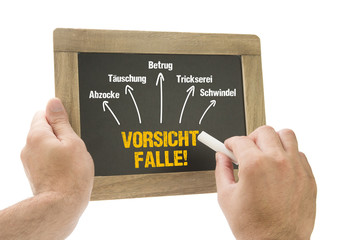 Hand schreibt Vorsicht Falle! auf Kreidetafel