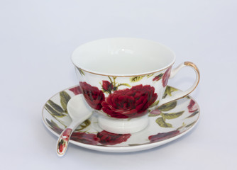 Porcelain cup with saucer and spoon on white background