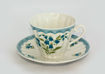 Porcelain cup with saucer and spoon on white background