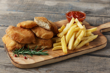  chicken nuggets french fries on the board with red sauce