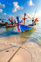 Fototapeta na wymiar Blue fishing wooden boat on the coast of the sandy beach
