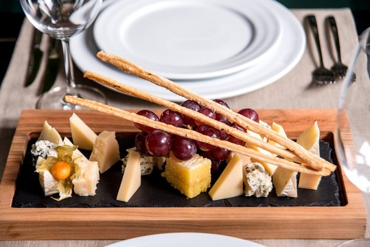 Assorted cheeses on a blackboard with a glass of wine in a restaurant. top view