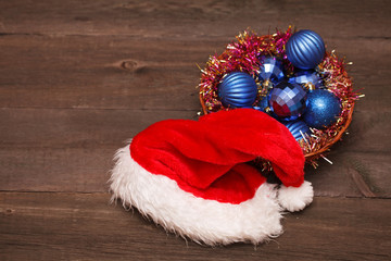 Obraz na płótnie Canvas Santa hats and blue Christmas balls on a wooden background