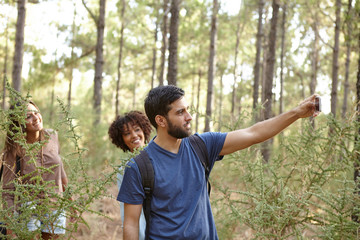 Young friends taking pictures in forest