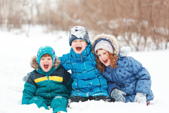 Laughing children sitting on a snow.