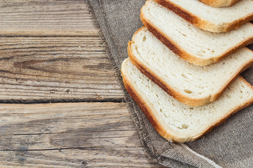 Pieces of white bread on sacking on an old wooden table.