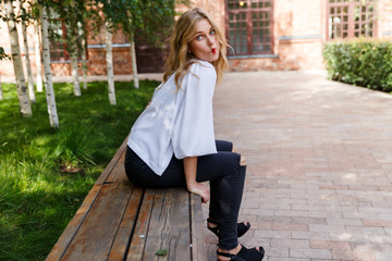 Young blond woman resting on bench and made bow lips