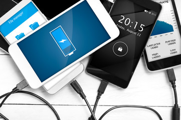 Stack of smartphones connected to power source. Concept of low battery level  problems