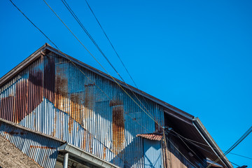 Obraz premium Old rusty galvanized iron plate house in countryside sunny day blue sky background.