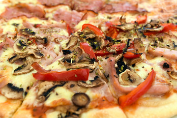 Pizza with mushrooms, ham, red pepper and herbs. Close-up.