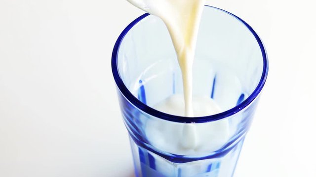 Pouring fresh milk into a blue glass. 