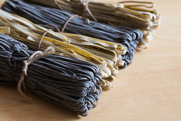Food. black and beige pasta, not cooked, wooden background