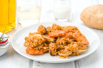 ration of rice with seafood in white plate on wood