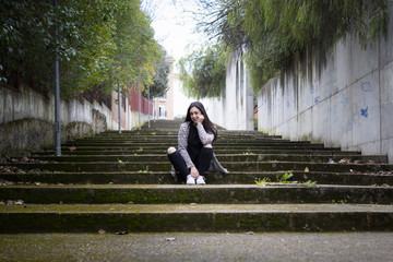 Chica joven morena subiendo y bajando feliz las escaleras en la ciudad. Modelo morena posando en...