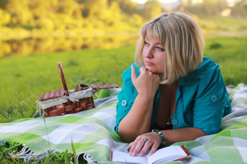 woman in park with book on the grass