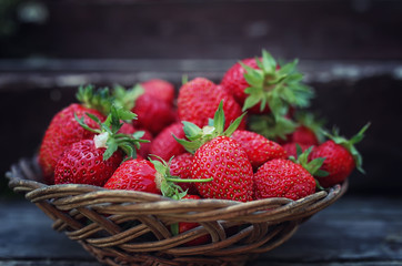 Strawberry in wicker plate on wooden background