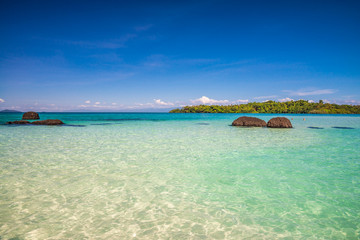 Obraz premium Beautiful tropical island beach in sunny day blue sky background. Summer tropical travel holiday vacation or green nature concept.