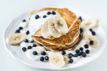 Homemade pancakes with banana, blueberries and sour cream