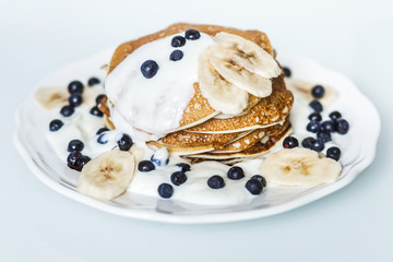Homemade pancakes with banana, blueberries and sour cream