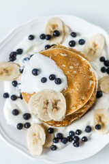 Homemade pancakes with banana, blueberries and sour cream