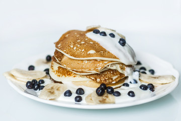 Homemade pancakes with banana, blueberries and sour cream