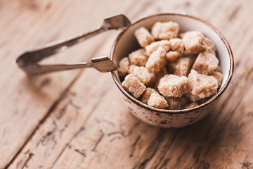 Saucer with brown sugar on the wooden background