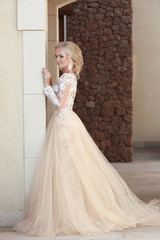 Obraz premium Elegant bride in fashion wedding dress posing by the wall. Attra