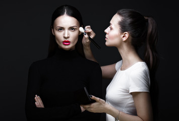 Two beautiful girls on a photo shoot to apply makeup to the face. Beauty fashion model. Photos shot...