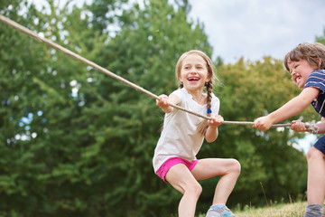 Junge und Mädchen beim Tauziehen