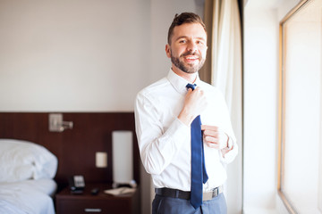 Latin businessman fixing his tie in a hotel