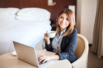 Cute businesswoman drinking some coffee in a hotel