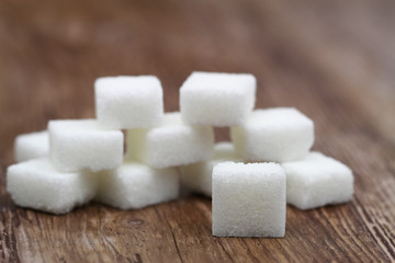 White sugar stacked up on wooden surface

