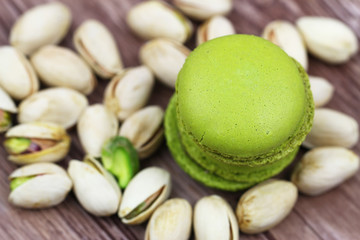 Crunchy pistachio macaroons stacked up on scattered pistachio nuts, close up
