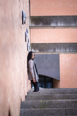 Chica joven morena subiendo y bajando feliz las escaleras en la ciudad. Modelo morena posando en las escaleras.