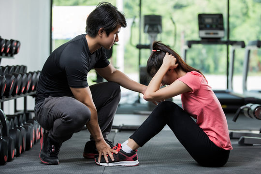 Trainer holding a woman in the leg exercise by Sit-up