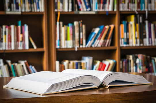 Open book on the table in a library and bookshelf