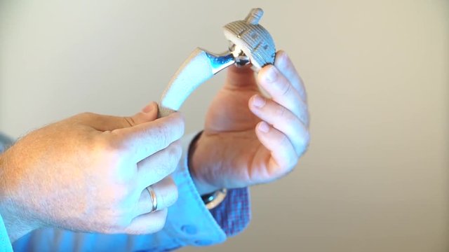 closeup a hip prosthesis in the hands of the doctor, he shows the principle of operation of prosthetic joints
