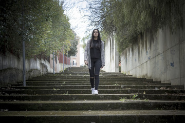 Chica joven morena subiendo y bajando feliz las escaleras en la ciudad. Modelo morena posando en las escaleras.