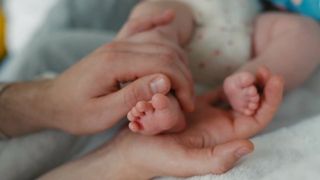 Father Holds his Tiny Baby's Toes In His Hand