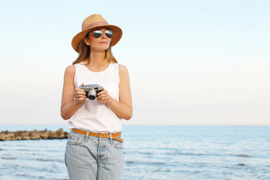 Enjoying summer vacation at the seaside. Woman with photo camera on the beach.