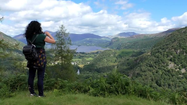 Woman on mount taking picture with smartphone of  the beautiful Derwentwater lake scenery in Lake District, England