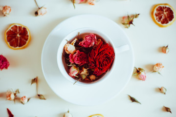 dried flowers dried roses and round slices of lemon laid on a white background and the white Cup