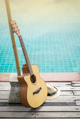 Acoustic guitar leaning on swiming pool.