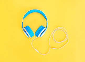Blue headphones lie on a colorful yellow background