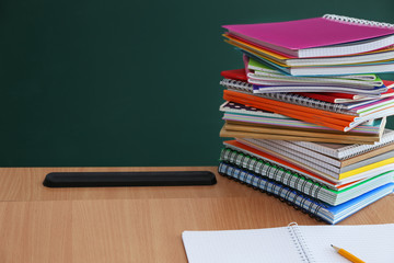 Stacked school notebooks on blackboard background